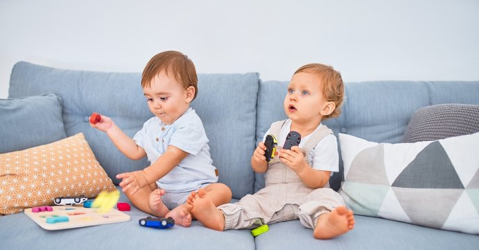 Beautiful toddlers sitting on the sofa playing with toys at home