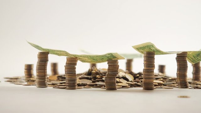 The concept of money. Columns of gold coins in the form of skyscrapers or Stonehenge. Close-up hands make up stacks of coins. Smoke. Garland.