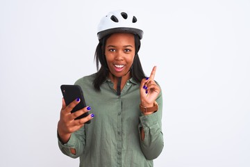 Young african american woman wearing bike helment and using smartphone surprised with an idea or question pointing finger with happy face, number one