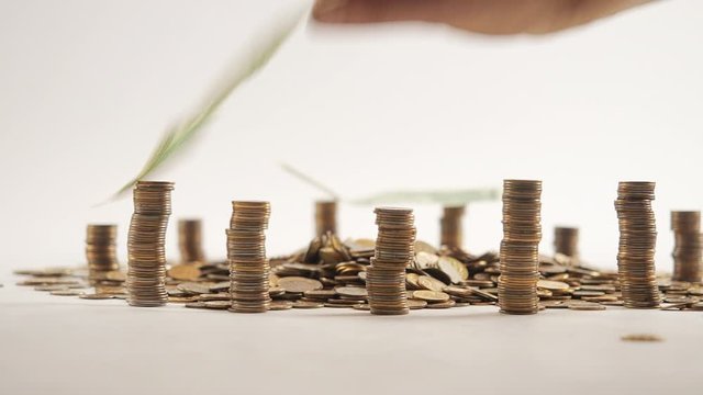 The concept of money. Columns of gold coins in the form of skyscrapers or Stonehenge. Close-up hands make up stacks of coins. Smoke. Garland.