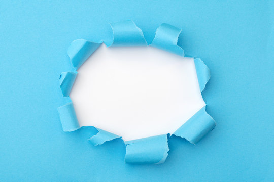 Blue paper with ripped hole in the middle background, flat lay