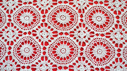 close up of a crochet doily on a red background