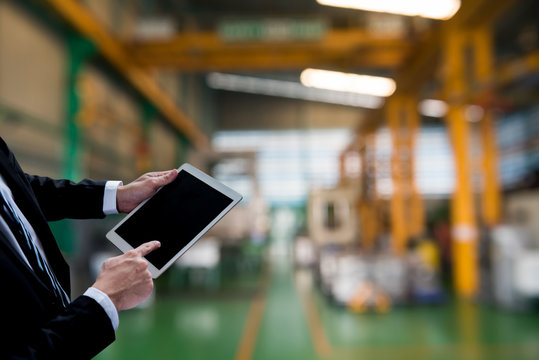 Business new technology and innovation for checking stock in the warehouse. Businessman using computer in the factory background.