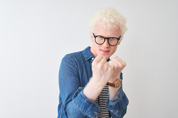 Young albino blond man wearing denim shirt and glasses over isolated white background Ready to fight with fist defense gesture, angry and upset face, afraid of problem