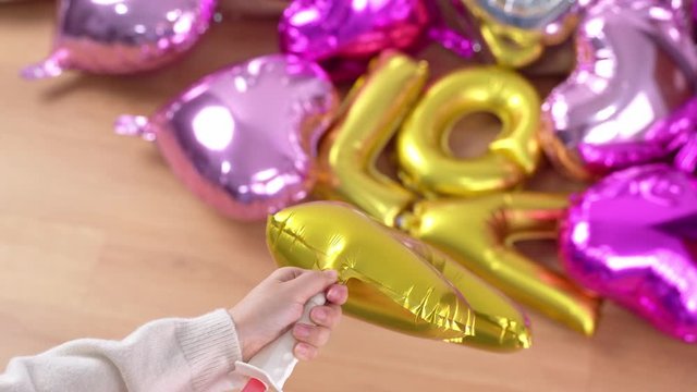Woman is manual pumping shaped balloon for preparing party decoration at home, close up, 4K, lifestyle.
