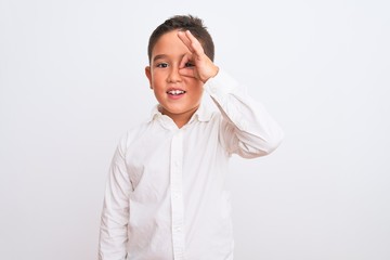 Beautiful kid boy wearing elegant shirt standing over isolated white background doing ok gesture with hand smiling, eye looking through fingers with happy face.
