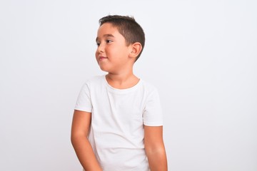 Beautiful kid boy wearing casual t-shirt standing over isolated white background smiling looking to the side and staring away thinking.