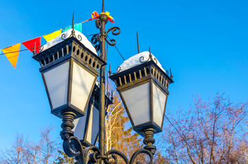 Lights and lanterns on a pole on a winter day under snow.