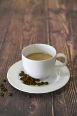 Cappuccino in white coffee cup on wooden table with dark roasted coffee bean