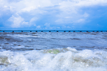 A bridge on the horizon. The seashore with boulders. Blue sky.