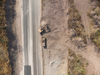 Aerial shot of excavator machine backhoe digging dirt and load filling soil to dump truck