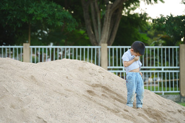 Fototapeta na wymiar Asian boy playing with sand and toy at public park