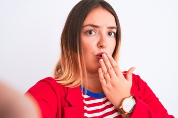 Beautiful woman wearing striped t-shirt and jacket standing over isolated white background cover mouth with hand shocked with shame for mistake, expression of fear, scared in silence, secret concept