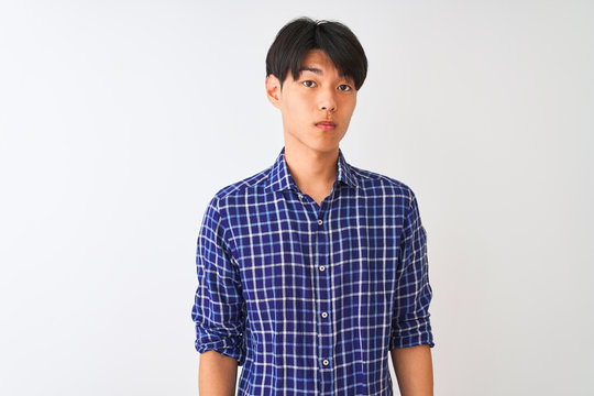 Young Chinese Man Wearing Casual Blue Shirt Standing Over Isolated White Background Relaxed With Serious Expression On Face. Simple And Natural Looking At The Camera.