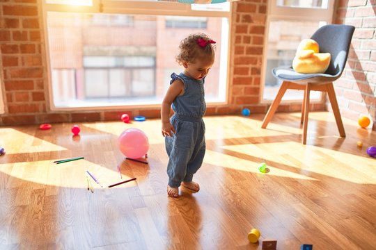 Beautiful caucasian infant playing with toys at colorful playroom. Happy and playful at kindergarten.