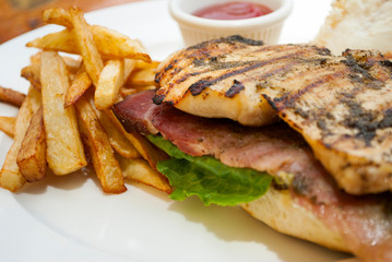  Sandwich prepared with grilled chicken with roast beef, french fries and tomato sauce, served outdoors on wooden table in Guatemala.
