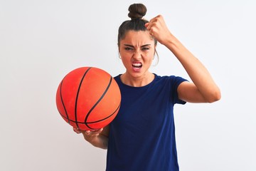 Young beautiful sportswoman holding basketball ball over isolated white background annoyed and frustrated shouting with anger, crazy and yelling with raised hand, anger concept
