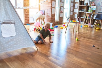Young caucasian kid playing at kindergarten with toys. Preschooler boy happy at playroom.