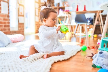 Fototapeta premium Beautiful infant happy at kindergarten around colorful toys