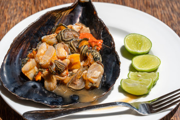 Raw clam meat in a large seashell served for food at a local restaurant on the island of Zanzibar, Tanzania, East Africa