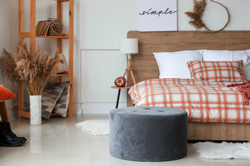 Stylish interior of room with big comfortable bed and autumn decor