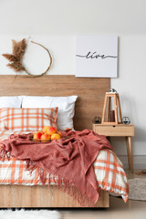 Obraz na płótnie Canvas Stylish interior of room with big comfortable bed and autumn decor