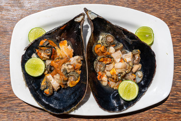 Raw clam meat in a large seashell served for food at a local restaurant on the island of Zanzibar, Tanzania, East Africa