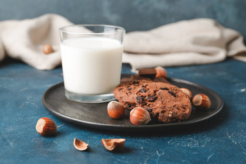 Tasty chocolate cookies with hazelnuts and glass of milk on dark background