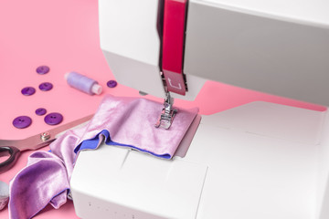 Sewing machine with supplies on color background, closeup