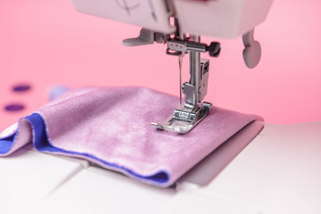 Sewing machine with cloth on color background, closeup