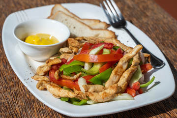 Roasted chicken fillet with vegetables and bread on a white plate, closeup