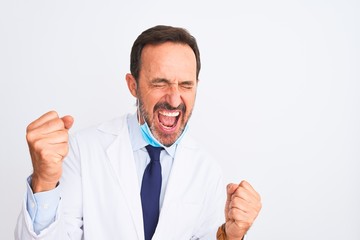 Middle age scientist man wearing coat and medical mask over isolated white background very happy and excited doing winner gesture with arms raised, smiling and screaming for success. Celebration