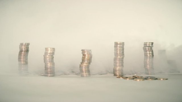 The concept of money. Columns of gold coins in the form of skyscrapers or Stonehenge. Close-up hands make up stacks of coins. Smoke. Garland.