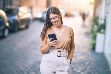 Obraz premium Young beautiful woman smiling happy and confident. Standing with smile on face using smartphone at the city
