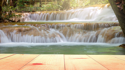 empty wooden table and waterfall at morning background