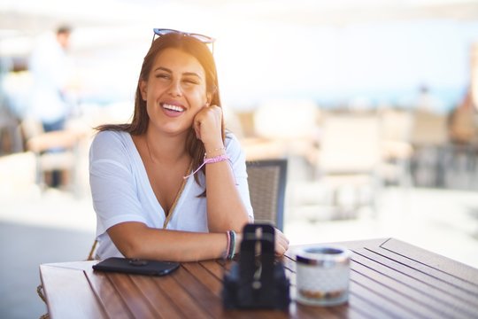 Young beautiful woman sitting at terrace of a restaurant smiling