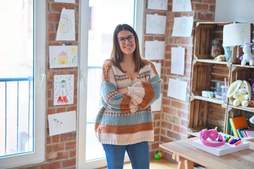 Young beautiful teacher woman smiling happy and confident. Standing with smile on face at kindergarten