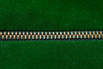 Gold zipper closed binding. Green textile under high magnification. Texture or background