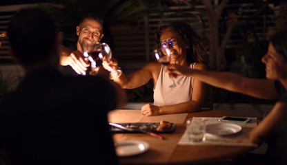 Beautiful family toasting with cup of wine on dinner smiling at terrace