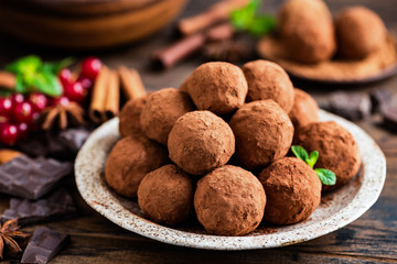 Raw dark chocolate truffles, homemade vegan and vegetarian chocolate on a plate, closeup view. Raw sweet food