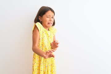 Young beautiful child girl wearing yellow floral dress standing over isolated white background...