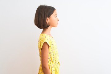 Young beautiful child girl wearing yellow floral dress standing over isolated white background...