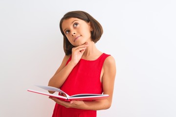 Beautiful student child girl reading red book standing over isolated white background serious face...