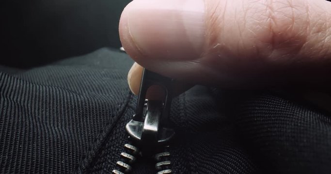 Close up of fingers zipping up a black jacket. Shot in 4K RAW on a cinema camera.