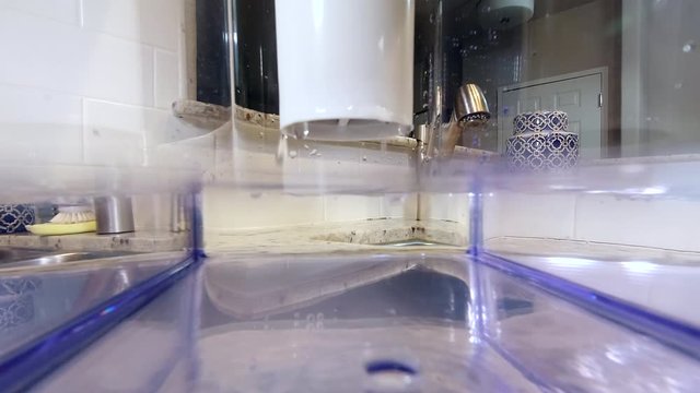 POV as camera begins to submerge inside water filtration pitcher as water drips in