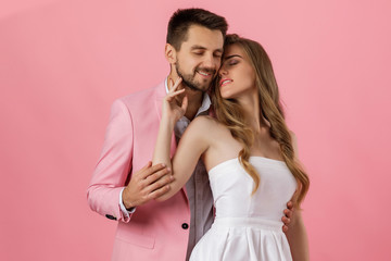 happy couple in love embracing on pink background. man in a jacket and a woman in a dress are happy together. st valentines day.