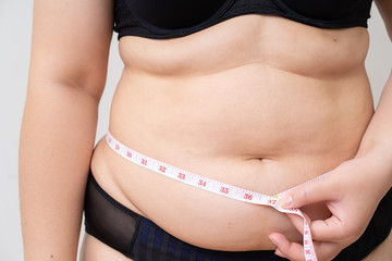 Overweight women with tape measuring her belly