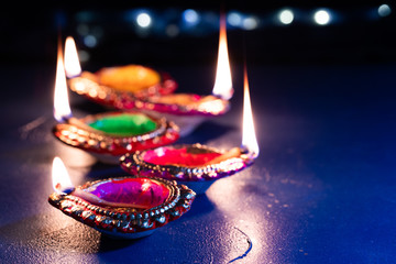 burning decorated ceramic oil lamp diya, on Happy Diwali, Shubh Diwali meaning with beautiful dark blue background, copy space
