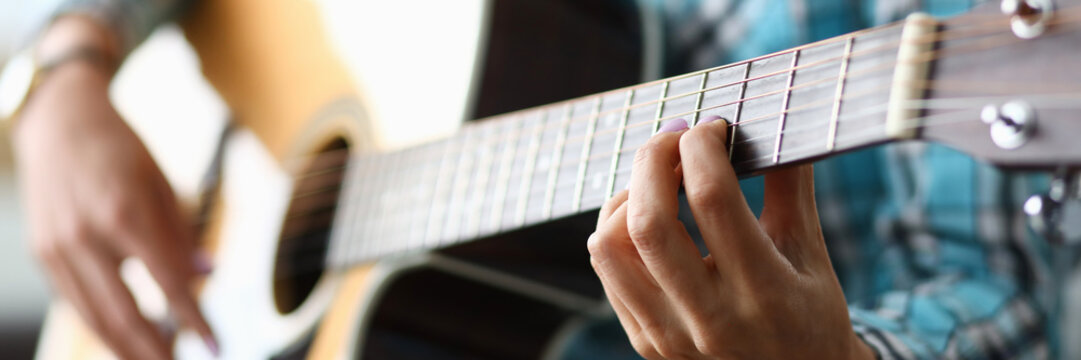 Focus on female hand playing bracket in music workshop. Professional guitar player having musical lesson for students. Art concept. Blurred background