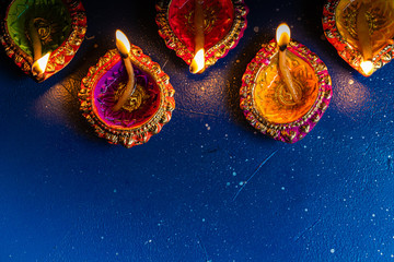 burning decorated ceramic oil lamp diya, on Happy Diwali, Shubh Diwali meaning with beautiful dark blue background, copy space
